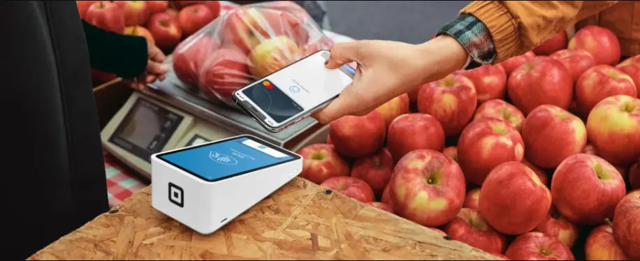 Square payment terminal being used for a mobile transaction at a fruit market.